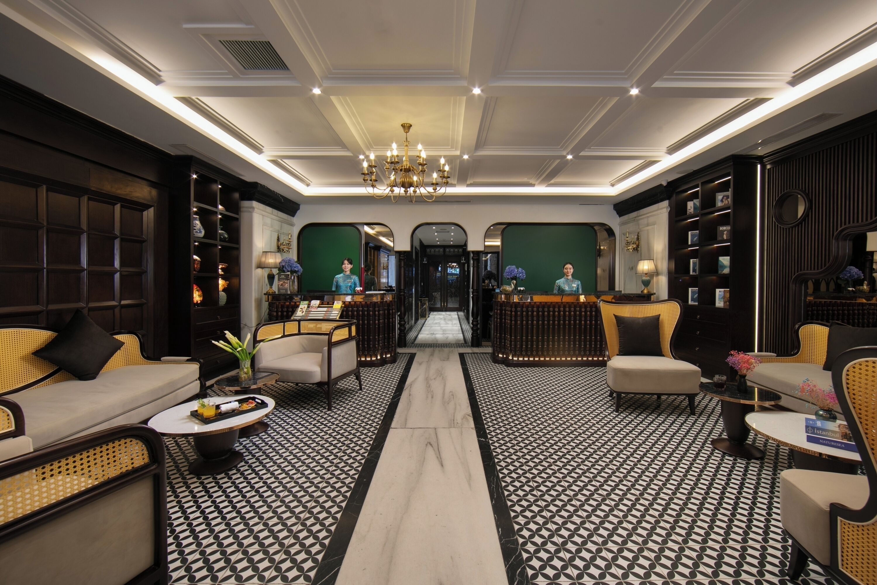 A lobby with a central chandelier, symmetrical seating, and a patterned floor.
