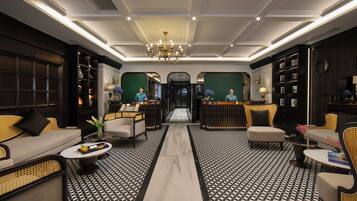 A lobby with a central chandelier, symmetrical seating, and a patterned floor.