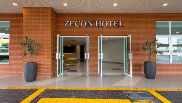 The entrance to ZECON HOTEL with a brick facade, glass doors, and potted plants. - Zecon Hotel (Kuala Lumpur)