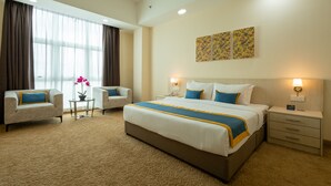 A hotel room with a large bed, two bedside tables, a small table with a flower, and a sofa. - Zecon Hotel (Kuala Lumpur)