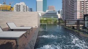 A rooftop pool with lounge chairs, a water feature, and city buildings in the background. - Passa Hotel Bangkok (Bangkok)