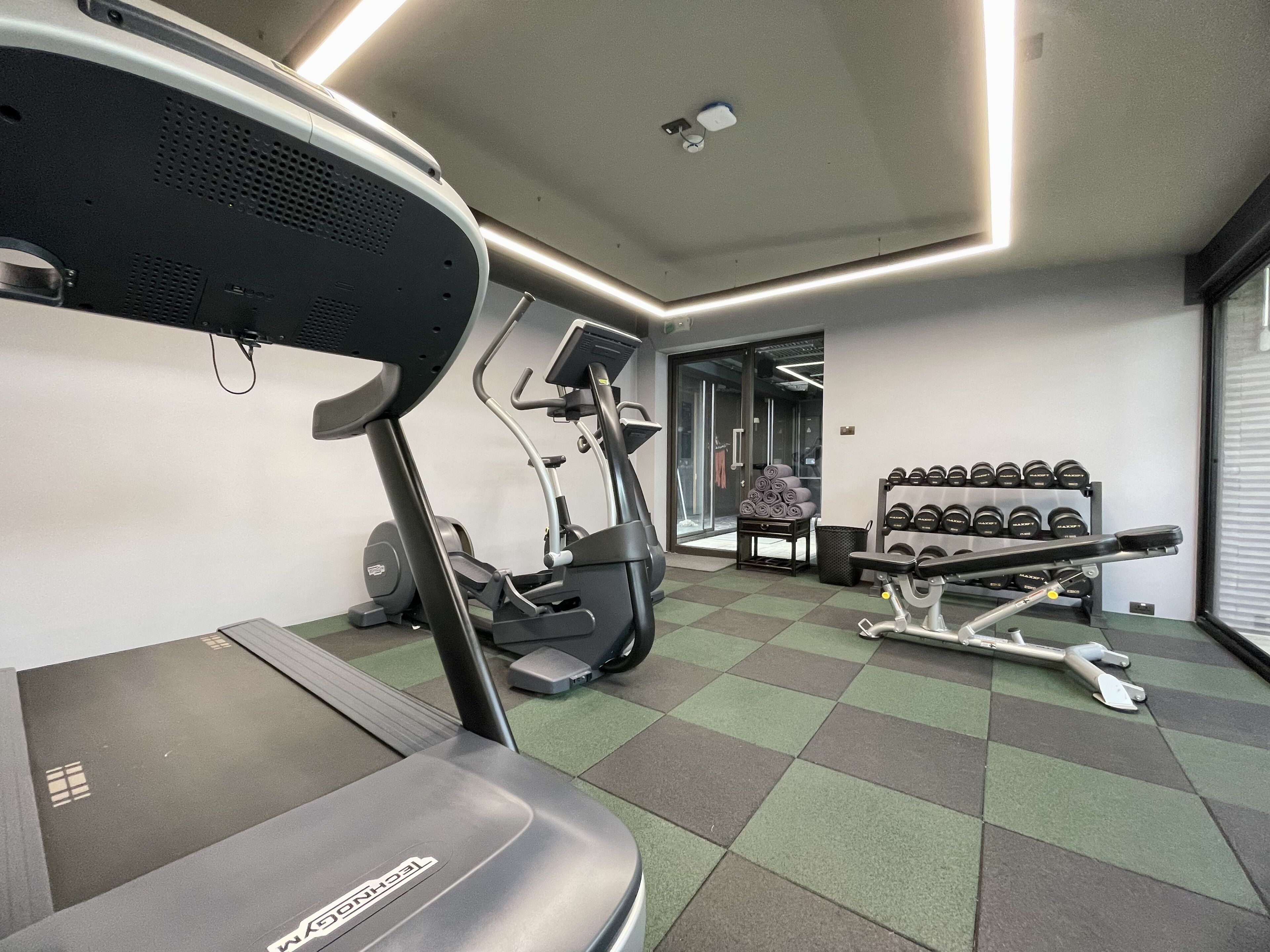 A gym with treadmills, weight machines, and dumbbells.