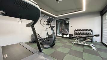 A gym with treadmills, weight machines, and dumbbells.