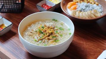 A bowl of rice with toppings, accompanied by small bowls of condiments and a bowl of fruit.