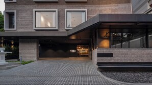 A modern building with a brick facade, large windows, and a covered entrance area. - Passa Hotel Bangkok (Bangkok)