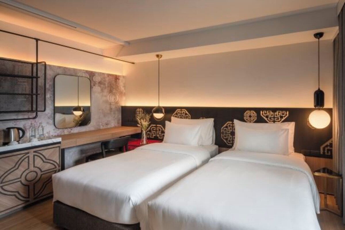 A hotel room with two beds, a desk, a mirror, and a decorative wall.