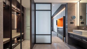 A modern bathroom with a large mirror, a sink, and a walk-in shower.