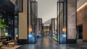 Un hall d’hôtel moderne avec un comptoir d’accueil central, un espace salon et une vue sur l’intérieur du bâtiment.