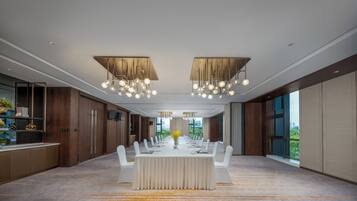 A modern dining room with a long table, white chairs, and a chandelier.