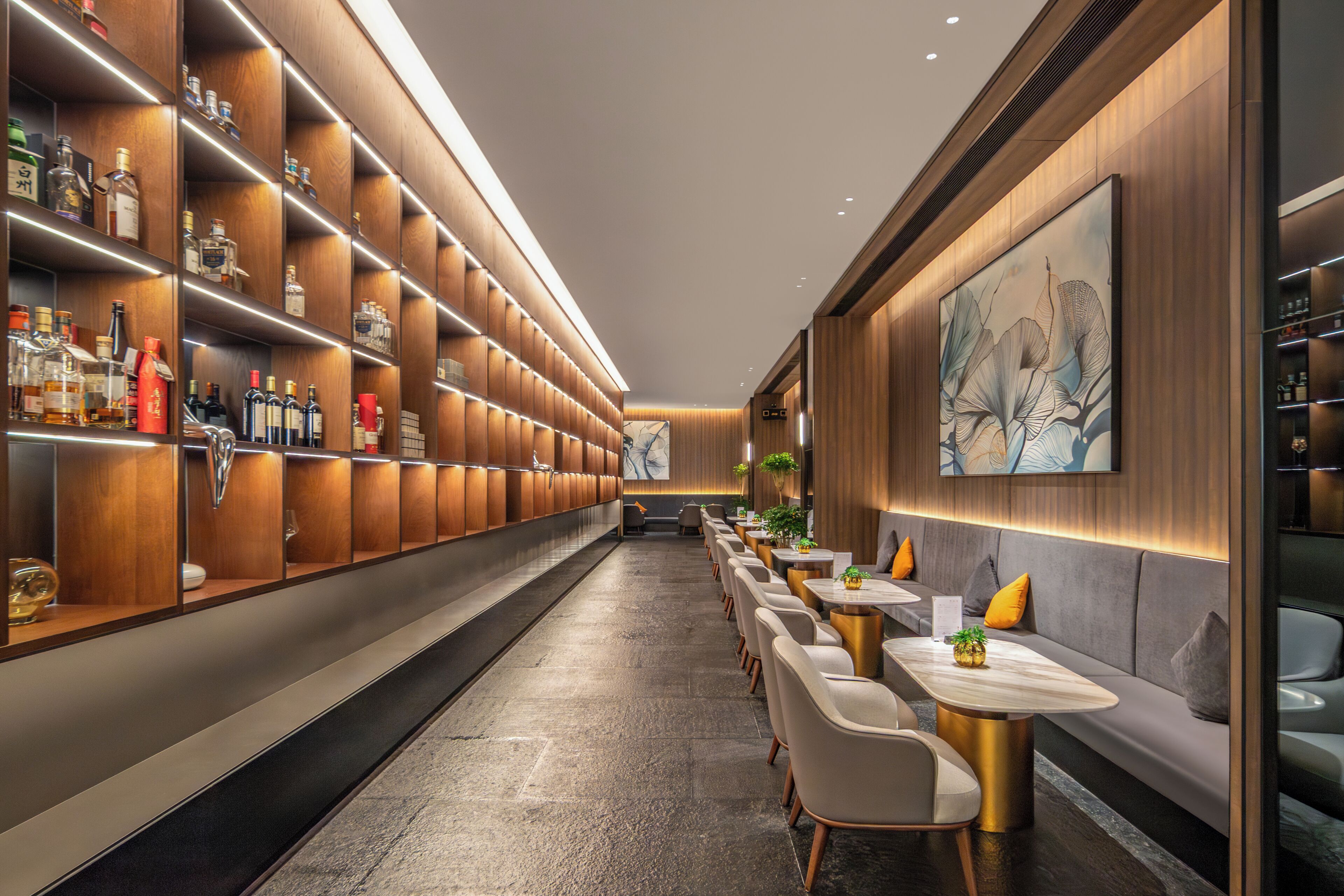 A modern bar area with wooden shelves, seating, and a large abstract painting on the wall.