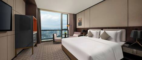A modern hotel room with a large bed, a TV, a desk, and a view of the city.