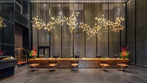 Un espace bar moderne doté d’un long comptoir, de nombreux tabourets et d’un luminaire suspendu original.