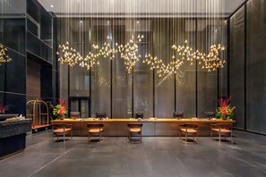 A modern bar area with a long counter, multiple stools, and a unique hanging light fixture. - Grand New Century Hotel, Wenzhou, A Tribute Portfolio Hotel (Wenzhou)