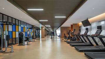 A gym with treadmills, weight machines, and a mirrored wall.