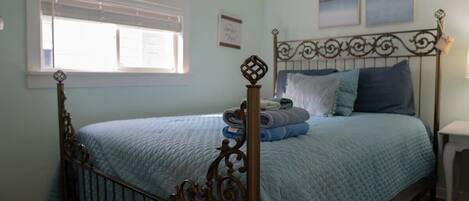 A bedroom with a bed, a window, and a nightstand.