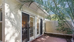A house with a brick patio, a white stucco exterior, and a black door with glass panels. - Guest Favorite Beckenham Townhouse, Walk to Beach, Pool, Private Courtyard, Port Royal Village (Hilton Head Island)