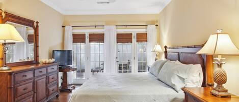 A hotel room with a bed, a television, a desk, and a view of the outside.