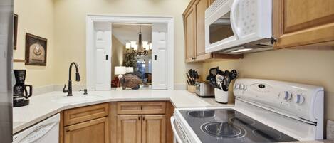 A kitchen with wooden cabinets, a white stove, a microwave, and a coffee maker.