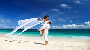 Una pareja en la playa, con cielos despejados y agua turquesa.