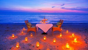 Mesa lista para dos con vista al océano al atardecer.