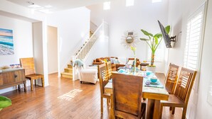 Un comedor amplio con una mesa y sillas de madera, una escalera y un espejo grande en la pared.