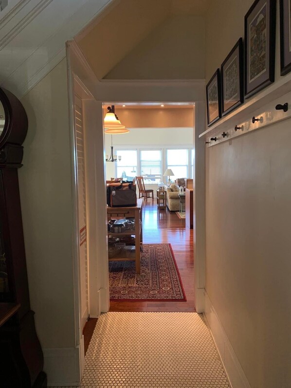 A hallway leading to a dining area with a wooden table and chairs, a rug, and a wall-mounted key rack. - Charming and spacious 2-story home with amazing views of the Columbia River. (Astoria)