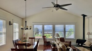 Una sala de estar amplia con comedor, ventanas grandes, ventilador de techo y chimenea.