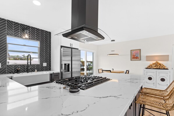 Uma cozinha moderna com uma ilha grande, eletrodomésticos de aço inoxidável e um backsplash com padrão herringbone.