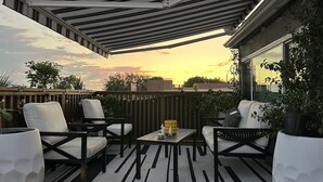 A covered outdoor seating area with a view of the sunset.