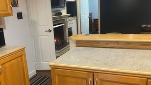 A kitchen with wooden cabinets, a countertop, and a built-in oven. - Your home away from home (Abbotsford)