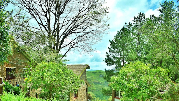 Edifici de pedra rústic amb una tanca de fusta i vegetació abundant.