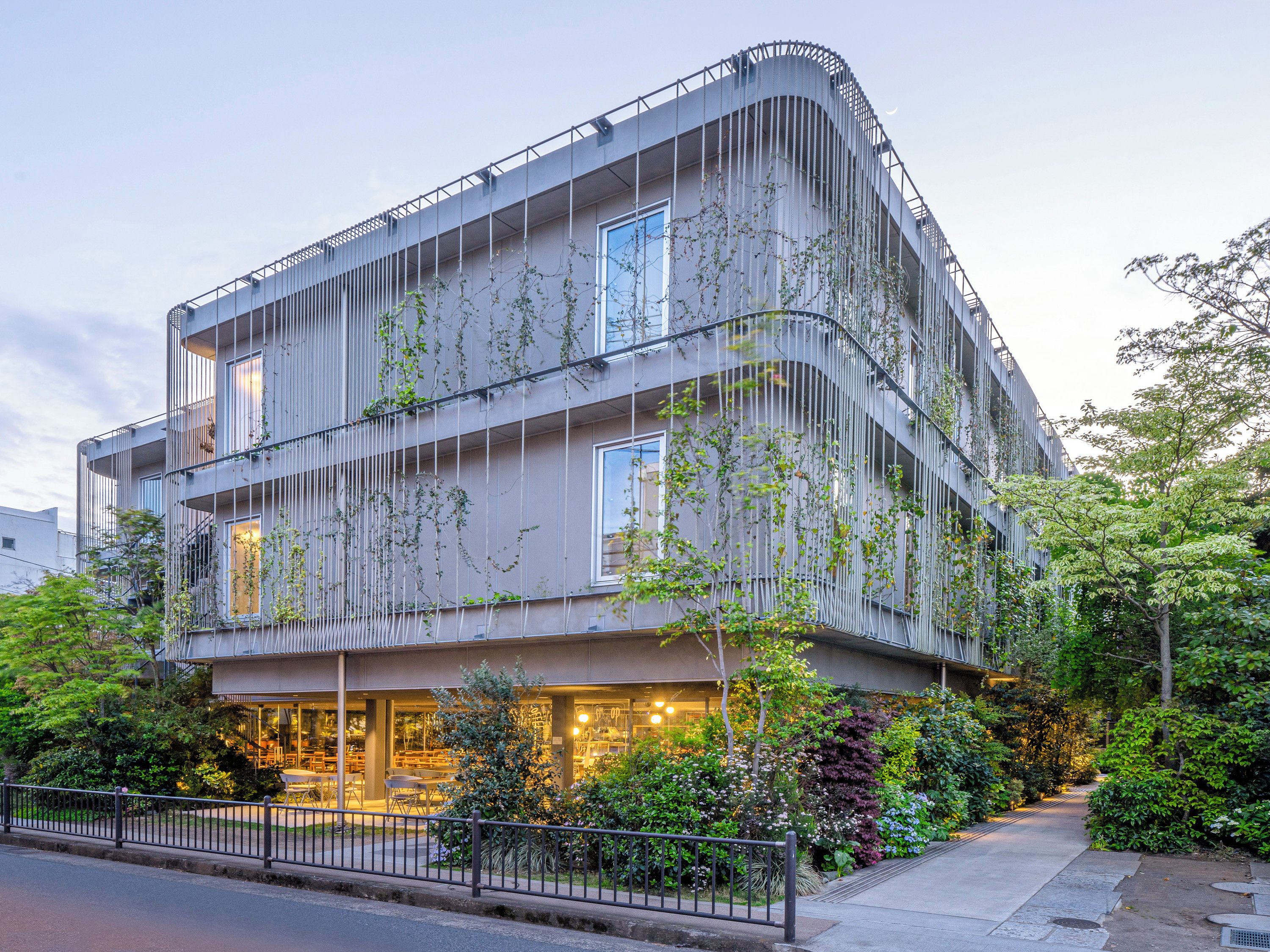 A multi-story building with balconies, a ground-level entrance, and a well-maintained garden area.