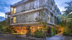 A multi-story building with a curved facade, large windows, and a ground-level entrance with outdoor seating.