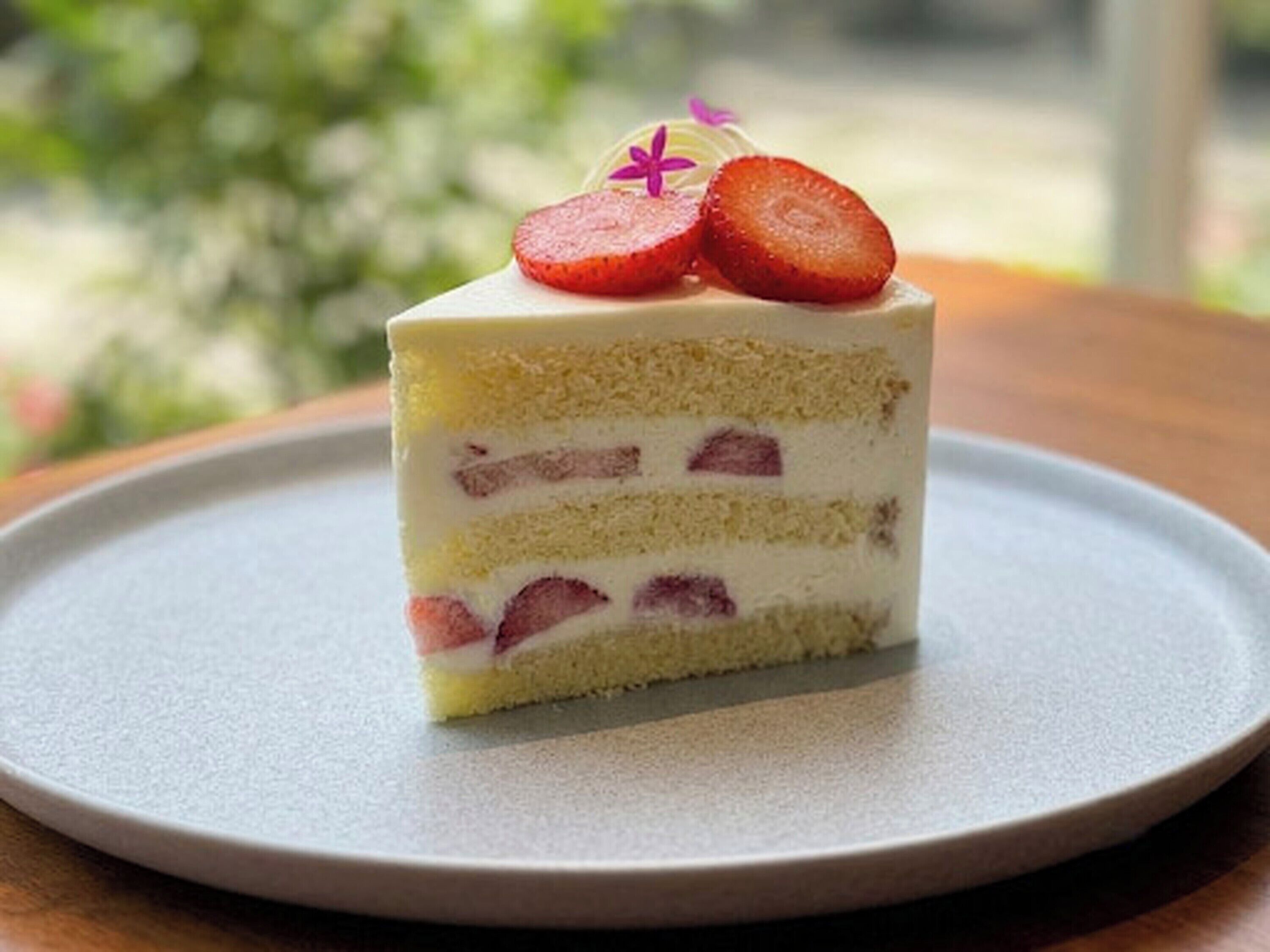 A slice of layered cake with strawberries on top, served on a plate.