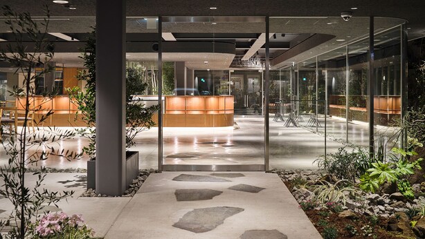 A modern lobby with a reception desk, seating area, and glass walls.