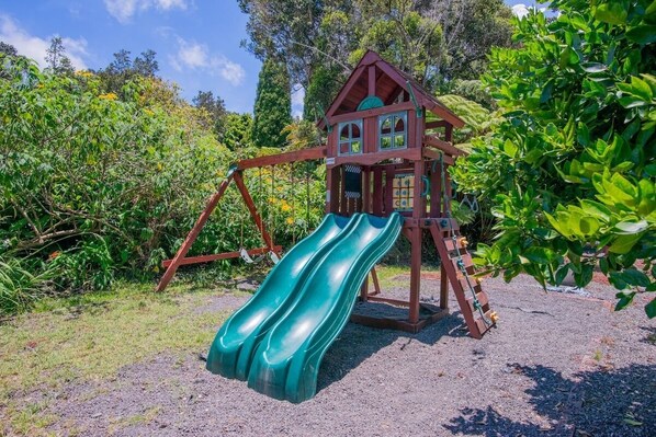 Une structure de jeu en bois dotée de deux toboggans et d’une échelle d’escalade.