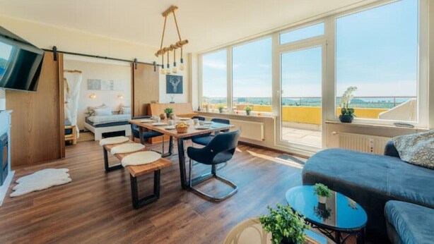 Una sala de estar moderna con comedor, ventanas grandes y vistas a la ciudad.