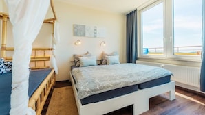 Un dormitorio con cama, mesita de noche, ventana con vistas y lámpara de pared.