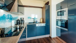 Una cocina moderna con armarios azules, electrodomésticos de acero inoxidable y suelo de madera.