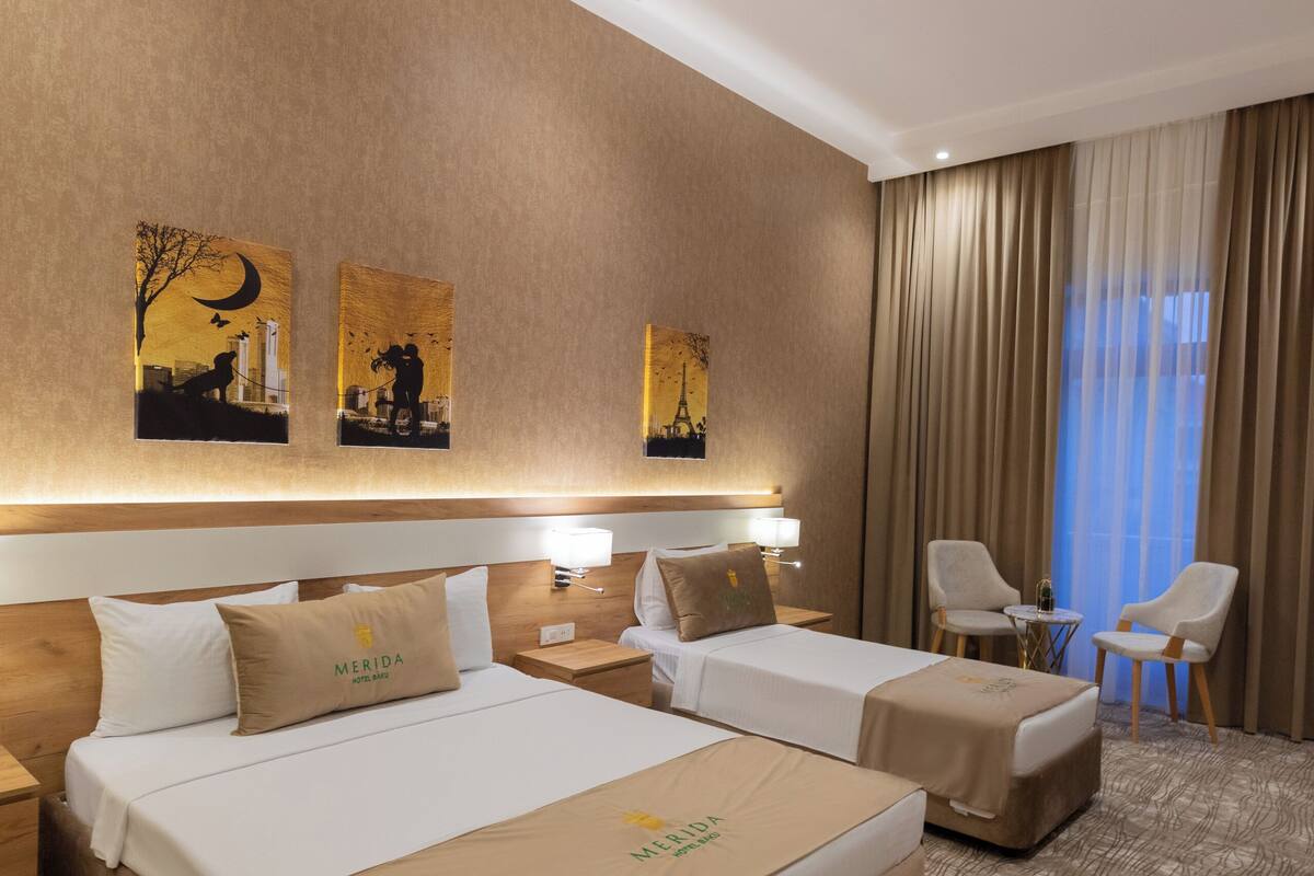 A hotel room with two beds, a desk, and a chair.