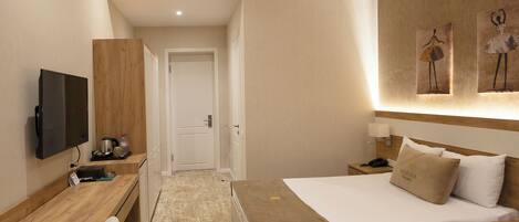 Habitación de hotel con cama, mesita de noche, escritorio, silla y televisor.
