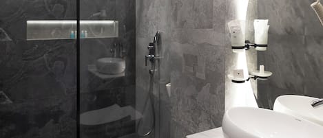 A modern bathroom with a glass-enclosed shower, a white toilet, and a large mirror.