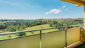 Un balcón con vistas a un paisaje verde y un cielo despejado.
