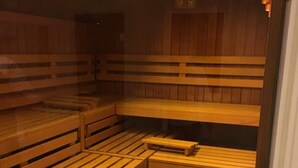 Una sauna con bancos de madera y un banco blanco pequeño.