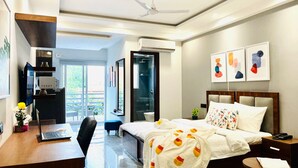 Habitación de hotel con escritorio, computadora portátil, cama y una obra de arte en la pared.