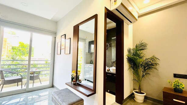 Habitación de hotel moderna con un espejo grande, una planta en maceta y vistas al exterior.