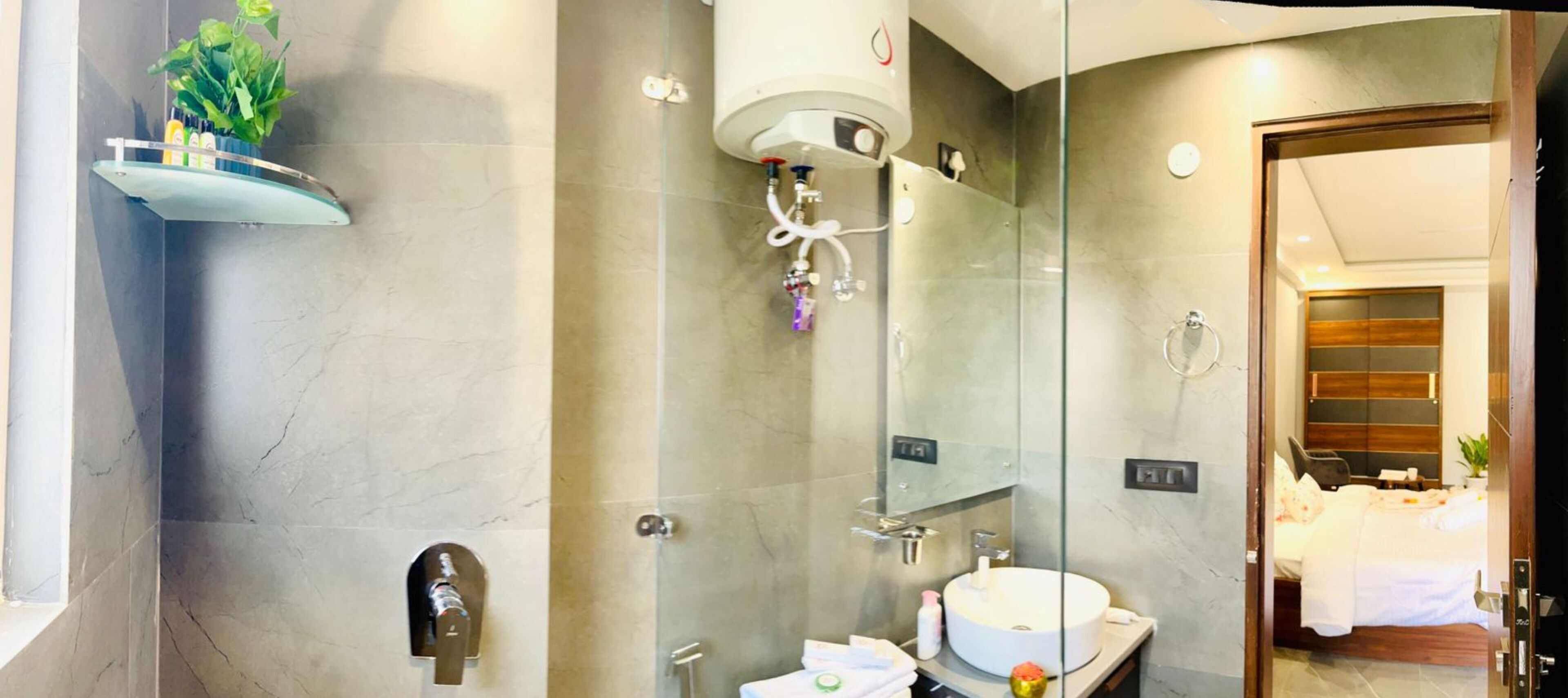 Een moderne badkamer met een douchecabine van glas, een rond wastafeltje en een handdoekrek.