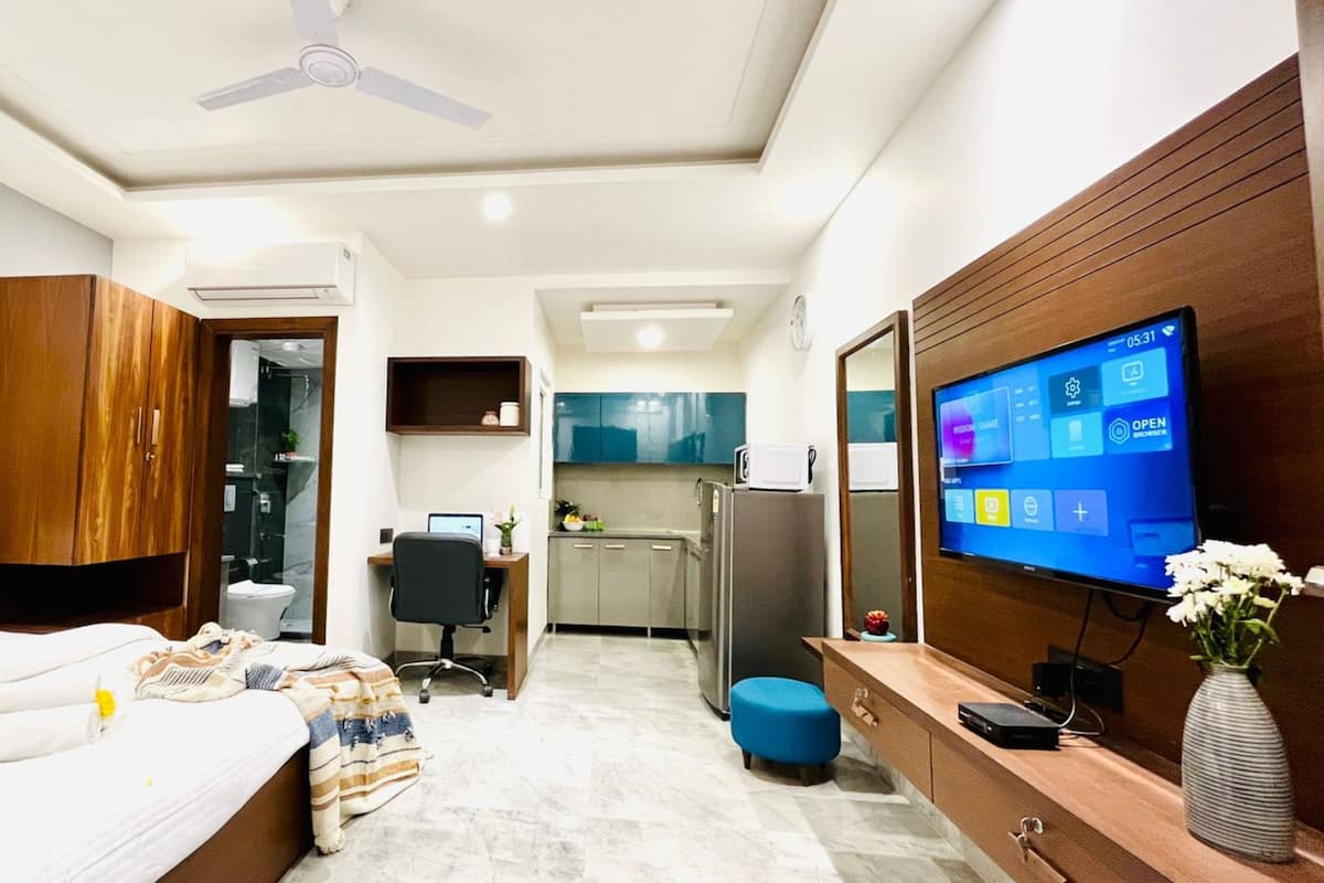 Une chambre d’hôtel moderne équipée d’un lit, d’un bureau, d’une télévision et d’une kitchenette.