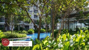 Piscina en un entorno natural rodeada de exuberante vegetación y edificios modernos.