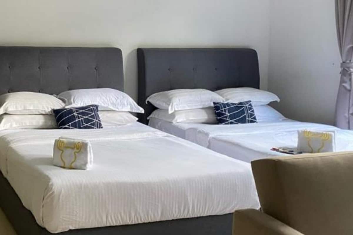 A hotel room with two beds, each with white bedding and decorative pillows.